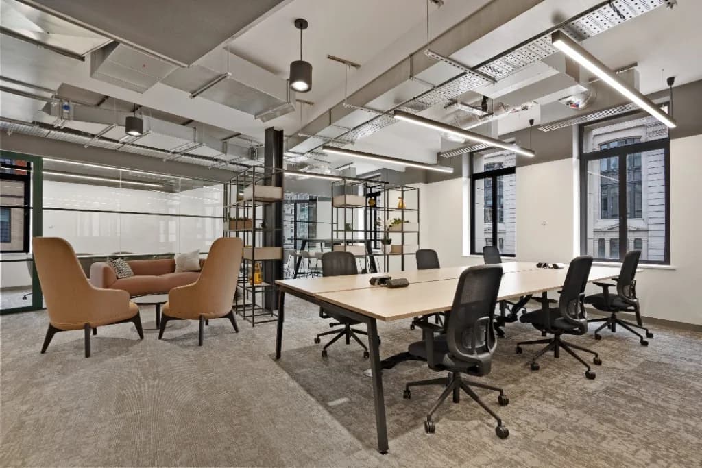 Open-plan commercial office with communal desks, breakout seating and industrial ceiling, photographed by Photoplan